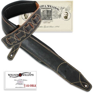 May include: Black leather guitar strap with brown leather accents and yellow stitching. The strap has a woven design and the text "WALKER & WILLIAMS Established 1894 Leather Goods Since 1894" is printed on a tag attached to the strap. The strap is labeled "C-22-DBLK".