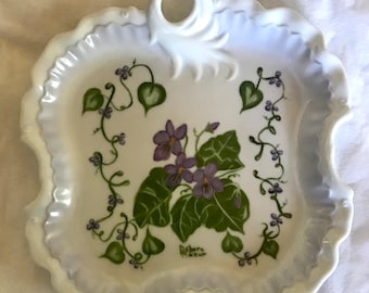 Preciosas violetas moradas en un plato de porcelana muy decorativo. Este es precioso.