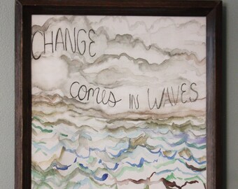 May include: A framed watercolor painting with a light blue, green, and brown wave pattern. The text "CHANGE comes in WAVES" is written in black ink.