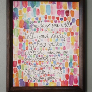 May include: A framed watercolor painting with a colorful background of pink, blue, yellow, and green. The painting features a handwritten quote that reads: "One day you will tell your story of how you've overcome what you are going through now, and it will become part of someone else's survival guide."