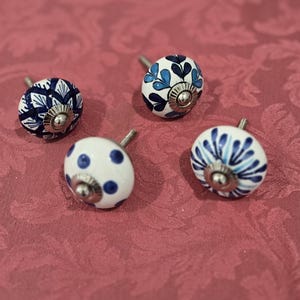 May include: Four ceramic knobs with blue and white designs. The knobs have a silver metal base and are perfect for adding a touch of farmhouse style to cabinets or drawers.