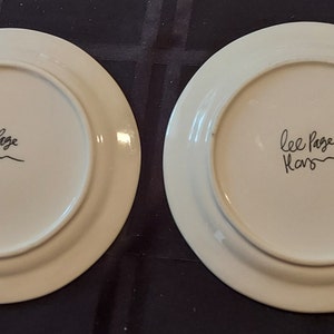 May include: Two white ceramic plates with a black handwritten signature that reads "Lee Page Kars".