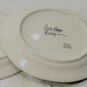 May include: White oval ceramic plate with black handwritten text "Lee Page Home" on the bottom. The plate has a black printed label with the text "Microwave, Oven, Dishwasher Safe" in a circle.