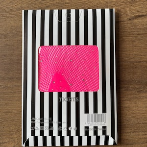 May include: Pink tights with a diamond pattern and a black and white striped packaging. The packaging includes the text "TIGHTS", "UNIQUE SIZE", "85% Polyamide 15% Elastane", and "MADE IN CHINA".