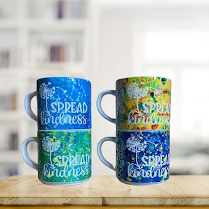 May include: Set of four colorful ceramic mugs with a dandelion design and the text "Spread kindness".