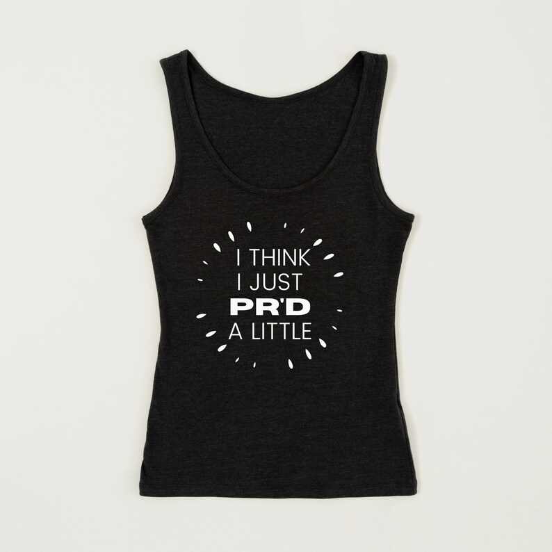 May include: Dark gray tank top with the text "I THINK I JUST PR'D A LITTLE" in white. The text is surrounded by small white dashes. The tank top has a scoop neck and is sleeveless.
