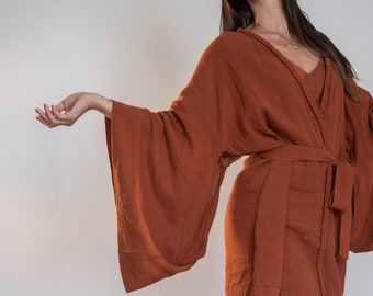 May include: A rust-colored linen robe with wide sleeves and a matching set of pants. The robe has a sash that ties at the waist.
