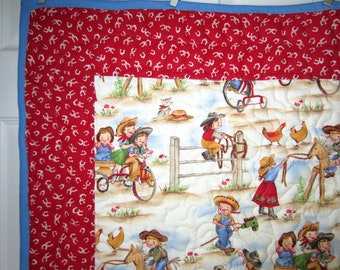 May include: A white and red patchwork quilt with a red border. The quilt features a white background with a pattern of children playing in a farm setting. The children are wearing cowboy hats and riding toy horses and tricycles. There are also chickens and a cat in the scene.