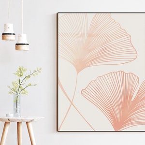 May include: A minimalist art print featuring two stylized ginkgo leaves in a soft peach color on a white background.