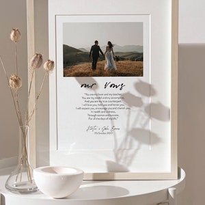 Puede incluir: Una impresi&oacute;n enmarcada de votos de boda con una foto en blanco y negro de una pareja caminando hacia la c&aacute;mara. Los votos est&aacute;n escritos en una fuente cursiva y el texto dice "Eres mi amante y mi maestro, Eres mi modelo y mi c&oacute;mplice, Y eres mi verdadera contraparte. Te amar&eacute;, te tendr&eacute; y te honrar&eacute;, Te respetar&eacute;, te animar&eacute; y te apreciar&eacute;, En la salud y en la enfermedad, En la tristeza y en el &eacute;xito, Por todos los d&iacute;as de mi vida." La impresi&oacute;n est&aacute; firmada "Katie & John Evans" y la fecha "25 de octubre de 2022".