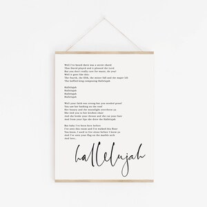 May include: Black and white printable wall art featuring the lyrics to the song "Hallelujah" by Leonard Cohen. The lyrics are printed in a simple font on a white background. The word "hallelujah" is written in a larger, more decorative font at the bottom of the page.