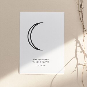 May include: A minimalist black and white print with a crescent moon design. The text "Wander Often Wander Always 07.07.20" is printed below the moon.