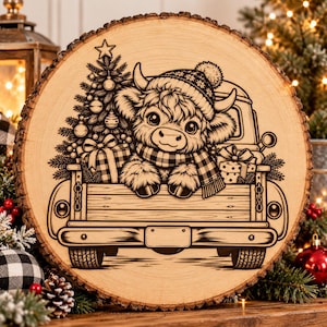 May include: A circular wood slice featuring a laser-engraved illustration of a fluffy Highland cow wearing a knit hat and scarf, sitting in the bed of a pickup truck. The truck bed contains a decorated Christmas tree and wrapped gifts.