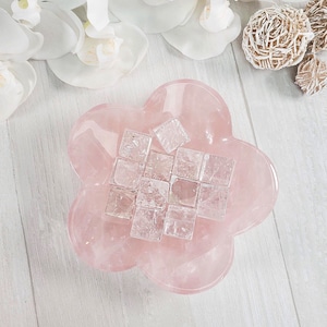 May include: A pink rose quartz bowl filled with clear quartz crystals. The bowl is shaped like a flower with five petals.