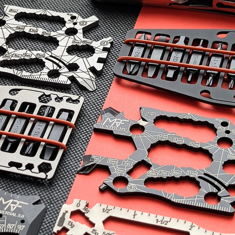 May include: A collection of multi-tools and bit sets in various shapes and sizes. The tools are silver and black, with measurements in millimeters and inches. Some tools have the text "MRF EXTREME" and "UNIVERSAL 3.0".