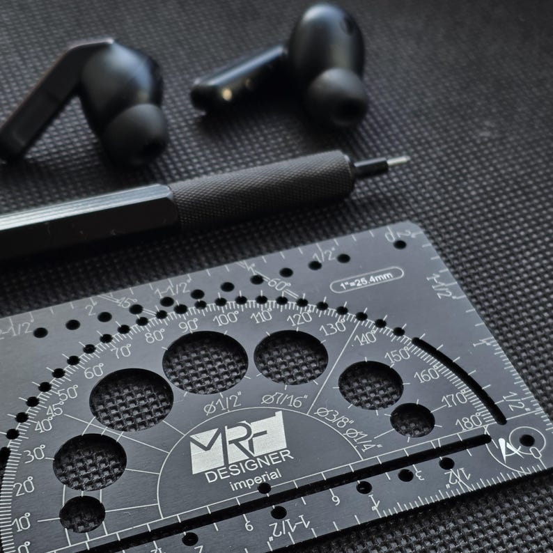 May include: A pair of black wireless earbuds, a black mechanical pencil, and a black metal drafting template tool featuring imperial measurements, degree markings, and circular cutouts with the text MRF DESIGNER imperial.