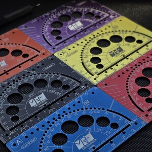 May include: A collection of multi-colored metal drafting templates featuring circular cutouts, protractor markings, and grid lines. Each tool is labeled with the MRF Designer logo and specific measurements in inches or centimeters.