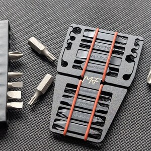 May include: A set of silver and black screwdriver bits, organized in a black holder and secured with orange rubber bands. The holder has labels with size specifications. The brand name "MR" is visible.