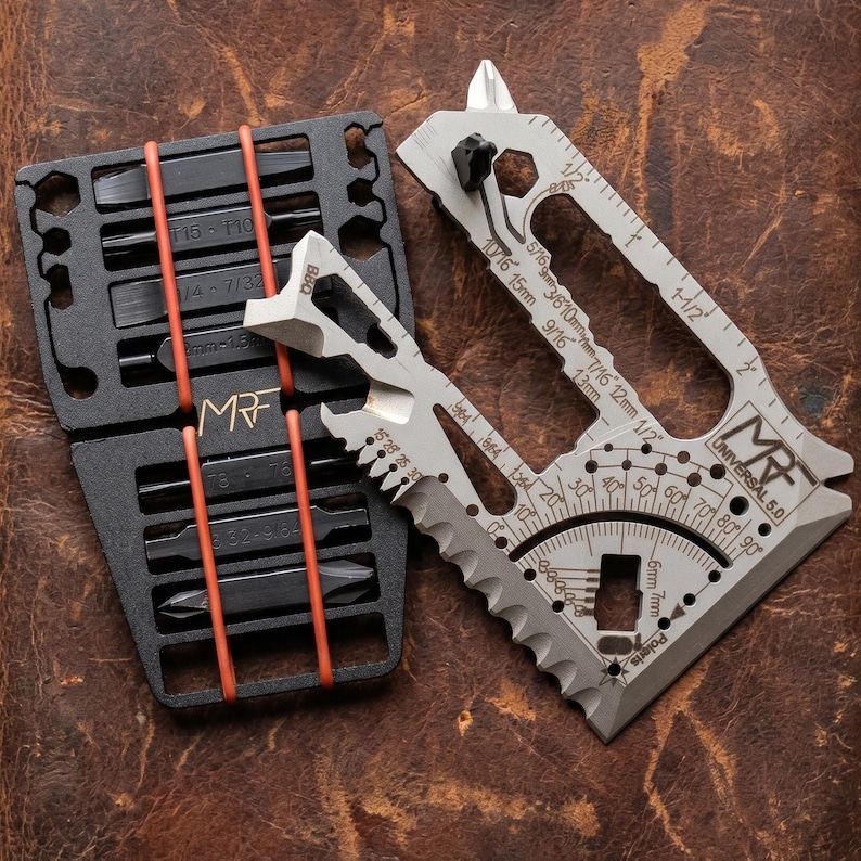 May include: A multi-tool set with a black bit holder and a silver multi-tool. The bit holder has orange rubber bands and the text "MRF". The silver tool has measurements and the text "UNIVERSAL 5.0".