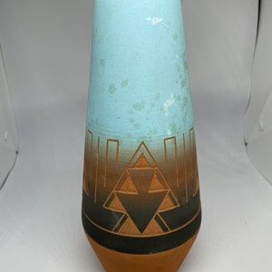 May include: A handmade ceramic vase with a light blue top and a brown base. The vase features a geometric design in shades of brown and black. The vase is approximately 10 inches tall.