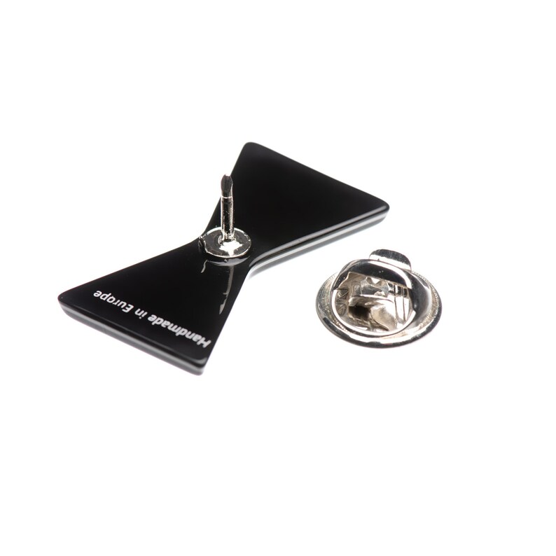 May include: Black bow tie pin with a silver pin back. The back of the pin says "Handmade in Europe".