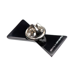 May include: Black bow tie pin with a silver pin back. The pin has the text "Handmade in Europe" on the back.