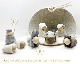 May include: A felt nativity scene set, including a stable, holy family, shepherd, sheep, donkey, and ox. The figures are made of felt and wood, with a neutral color palette. The text on the image reads "SET A+C+D".
