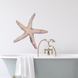 Peut inclure: Une baignoire à pieds en blanc avec un robinet doré et une serviette posée sur le côté. Un autocollant en forme d'étoile de mer en aquarelle est sur le mur au-dessus de la baignoire. Un pichet blanc avec des fleurs roses est sur le sol à côté de la baignoire.