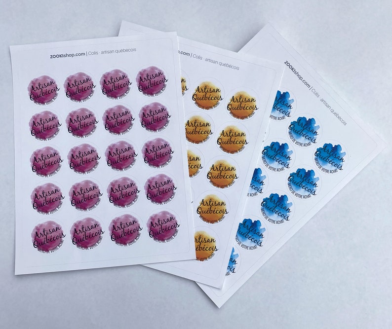 May include: Three sheets of stickers with the text "Artisan Qu&eacute;b&eacute;cois" in a watercolor-style font. The stickers are in three different color schemes: pink, orange, and blue.
