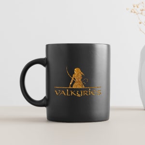 May include: Black ceramic mug featuring a gold glitter design of a woman holding a sword and the text "VALKYRIES".