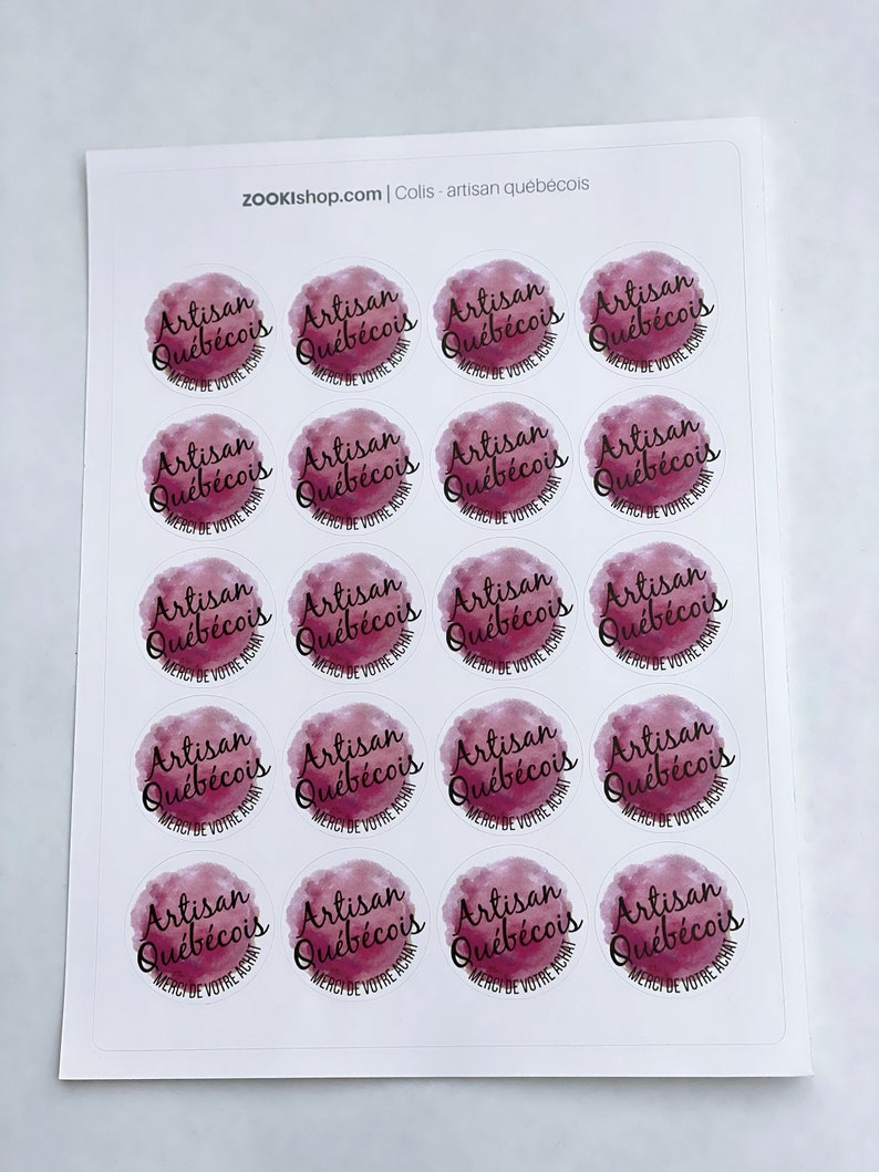 May include: Sheet of 16 round stickers with a watercolor design in shades of pink and purple. The stickers feature the text "Artisan Qu&eacute;b&eacute;cois" in black lettering with the words "Merci de votre achat" underneath.