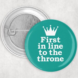 May include: A teal blue button with a white crown and the text "First in line to the throne".