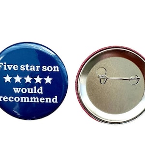 Op de afbeelding: Een blauwe knop met witte tekst die "Five star son would recommend" en vijf witte sterren zegt. De achterkant van de knop is zilver met een pin.