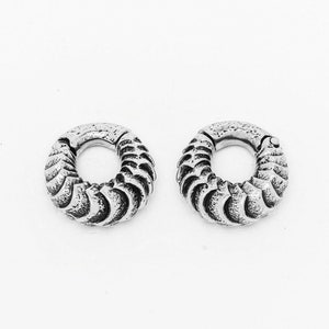 Puede incluir: Dos pendientes de aro plateados con un diseño texturizado en forma de onda.