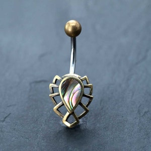 Puede incluir: Un piercing de ombligo de oro con una concha de abulón en forma de lágrima engastada en un marco decorativo.