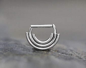 May include: A silver triple hoop septum ring with a hinged bar. The ring is made of surgical steel and is designed for septum piercings.