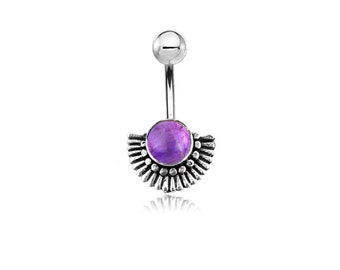 Peut inclure: Un piercing de nombril argenté avec une pierre précieuse violette et un motif de soleil. La bague a une barre incurvée avec une petite boule en haut et un pendentif décoratif en demi-cercle en bas.
