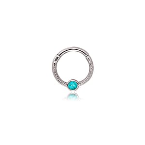 May include: A silver-colored hinged hoop earring with a textured band and a small, round, turquoise-colored stone set at the bottom. The earring is designed to be worn in a piercing.