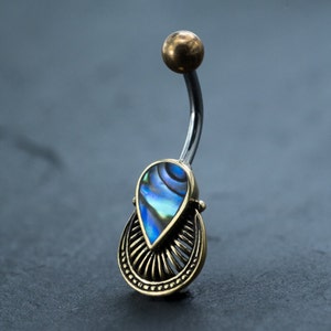 May include: A silver belly button ring with a gold abalone shell pendant. The pendant has a decorative design with a teardrop shape.