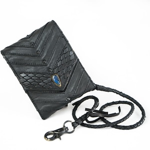 Peut inclure: Portefeuille en cuir noir avec un design géométrique unique, avec un motif de peau de serpent texturé et un accent de pierre précieuse bleue. Comprend une lanière en cuir tressé avec un fermoir en métal.