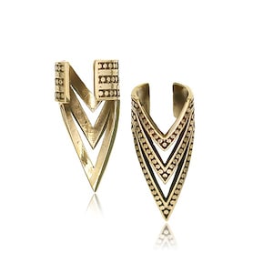 May include: A pair of gold-colored earrings with a geometric, V-shaped design. Each earring features a series of layered chevrons and small, dotted details. The earrings have a post and a decorative top.