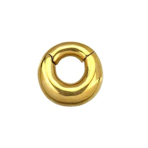 May include: A gold-colored, circular earring with a hinged clasp. The earring is a thick, rounded ring shape, with a smooth, polished surface. The clasp is visible at the top, allowing the earring to open and close. The earring is set against a white background.