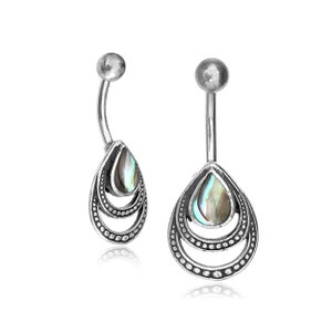 以下が含まれることがあります： アバロンシェルチャームが付いたシルバーのへそピアスのペア。チャームは、3つの同心円を持つシルバーフレームです。