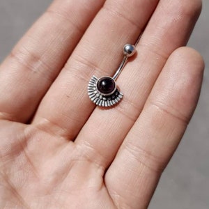 Può includere: Un piercing per l'ombelico in argento con una pietra preziosa nera e un design a forma di ventaglio.