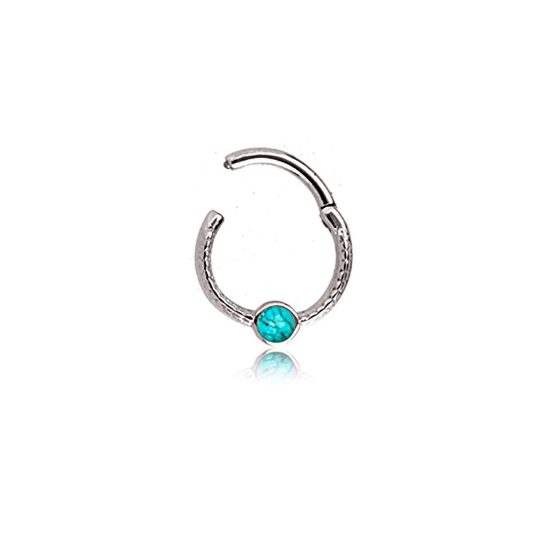 May include: A silver-colored hinged hoop earring with a textured surface. The earring features a small, round, turquoise-colored stone at the center. The earring is open, showing the hinged mechanism.