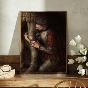 Könnte beinhalten: Ein gerahmter Druck, der eine mittelalterliche Szene darstellt. Eine Person in roter und silberner Rüstung kniet nieder und berührt das Bein einer anderen Figur in voller Rüstung. Das Kunstwerk hat eine dunkle, dramatische Ästhetik mit einem goldfarbenen Rahmen.