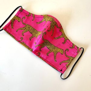 May include: A pink face mask with a leopard print pattern. The mask has black elastic ear loops.