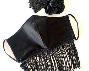 May include: Black face mask with a black fringe trim and a black beaded flower embellishment.