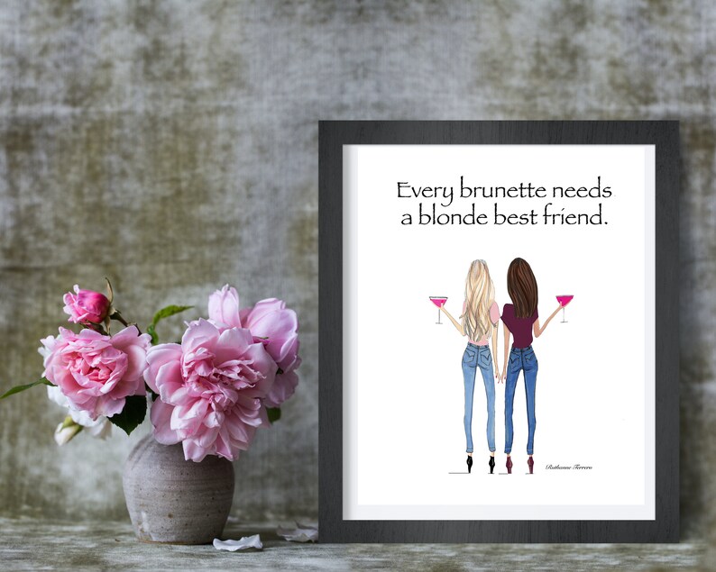 Puede incluir: Una impresi&oacute;n enmarcada con un fondo blanco que presenta una ilustraci&oacute;n de dibujos animados de dos mujeres, una con cabello rubio y otra con cabello casta&ntilde;o, sosteniendo c&oacute;cteles rosas. El texto "Every brunette needs a blonde best friend." est&aacute; impreso debajo de la ilustraci&oacute;n.