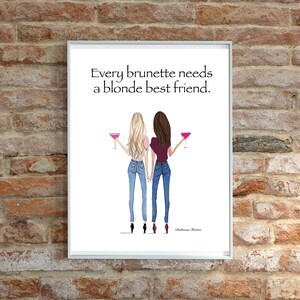 Puede incluir: Una impresi&oacute;n enmarcada en blanco con una cita que dice "Every brunette needs a blonde best friend." La impresi&oacute;n presenta una ilustraci&oacute;n de dibujos animados de dos mujeres, una con cabello rubio y otra con cabello casta&ntilde;o, ambas con jeans y sosteniendo c&oacute;cteles rosados.